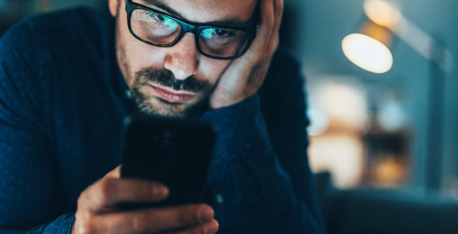 Man looking down at phone reading.