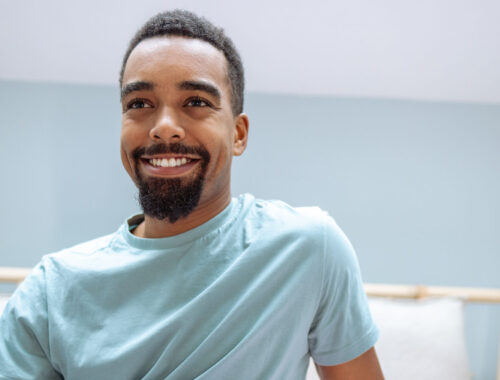 Handsome young African American man waking up in bed with smile