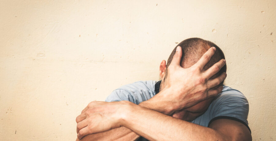 person sitting down and holding their head in their hands