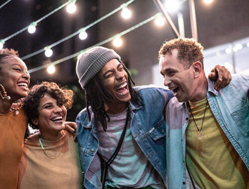 Friends embracing having fun in the street at night