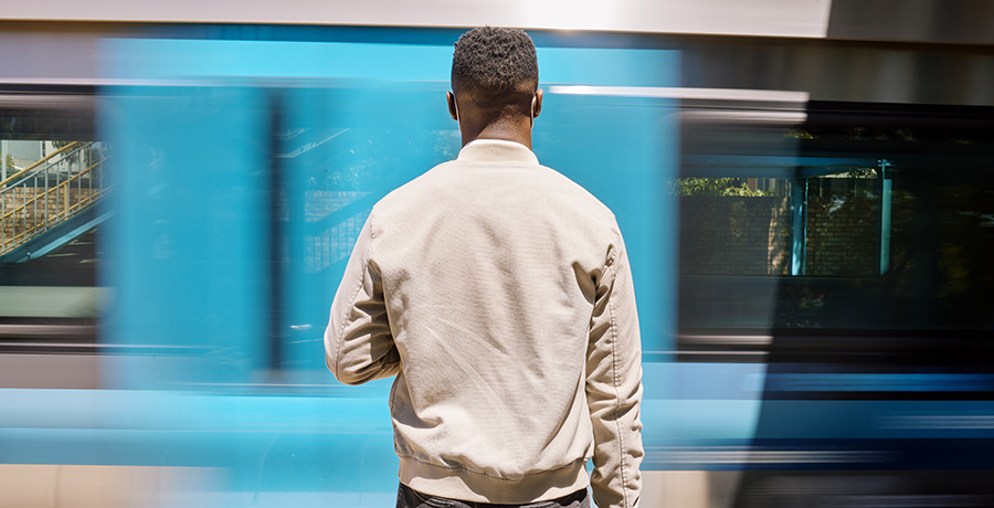 Black man facing away from the camera, waiting for public transportation